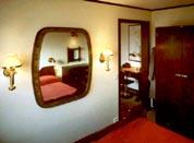 Part of a hotel suite furnished with restored 20th century original ship's bunk beds, wardrobe, desk, chairs, porthole-mirror and newly made brass lamps.