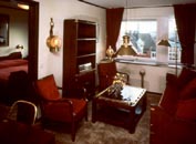 Part of a hotel suite furnished with restored 20th Century original ship's bunk beds, bookcase, desk, swivel-chair, armchairs, sofa table and newly made brass lamps.