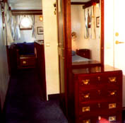 Part of a suite onboard a hotel ship, furnished with restored 20th century ship's chest of drawers, wardrobe, mirror, bunk bed, king-size bed, bedside table and newly made brass lamps.