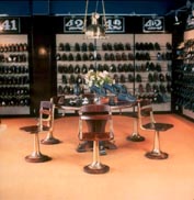Part of a shoe shop furnished with restored 20th century ship's table, swivel-chairs illuminated with an original deck light.