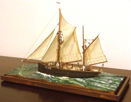 Maria LL225. North Sea fishing cutter with set sails. Depicting a busy crew handling freshly caught herring on deck. 20th century model. Mounted in a glass case.