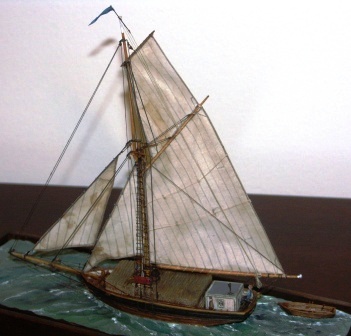 Sofia av Länna. Archipelago cargo boat with set sails and including crew members and a load of timber logs. 20th century model. Mounted in a glass case.