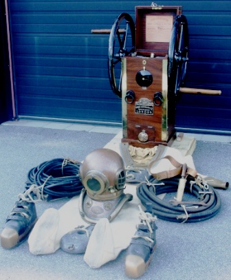 Early 20th century complete professional diving gear made by Siebe Gorman & Co Submarine Engineers London containing; single cylinder double-acting air supply hand-pump, 6-bolt copper helmet and corselet with matching number 14616, matching twill suit, front and back lead weights, knife with wooden handle and brass sheat mounted on leather belt, lead boots with brass toe caps and laces, jock strap with brass hangers, air line 50ft., corselet “T” spanner and air line spanner as well as telephone cable 200ft. with sealing caps.