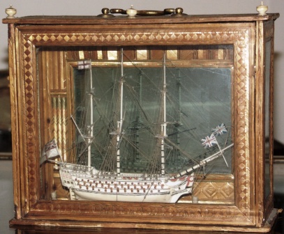 A very fine and detailed early 19th century prisoner-of-war bone model of a 98-gun ship-of-the-line. Mounted in wooden carrying case applied with coloured straw, also made by prisoners-of-war. Furnished with mirrored back panel to inspect the far side of the model.