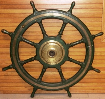 Early 20th century eight-spoked greenpainted ships wheel. Made of oak. With double brass bands and central brass hub.